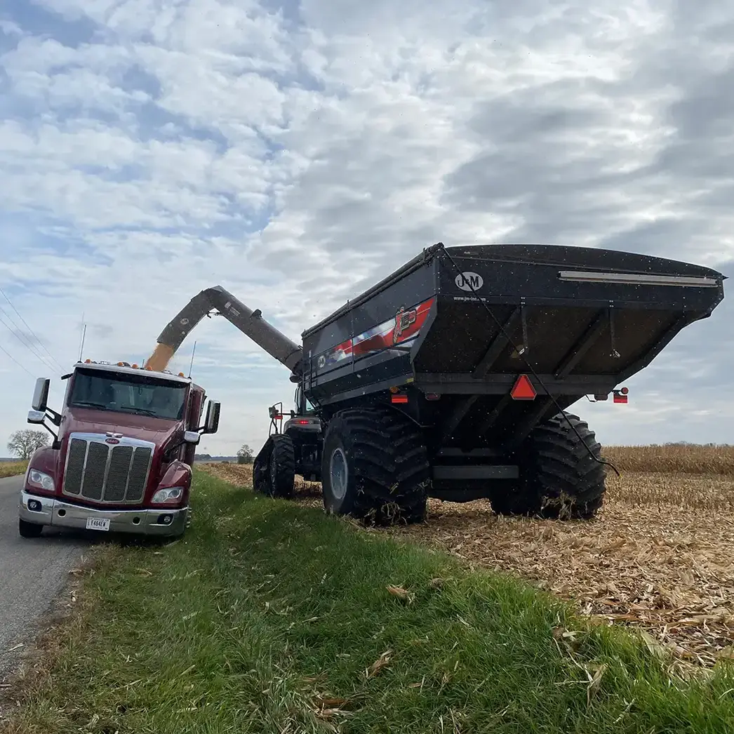 Black Patriotic Farmer Grain Cart Unloading over Ditch