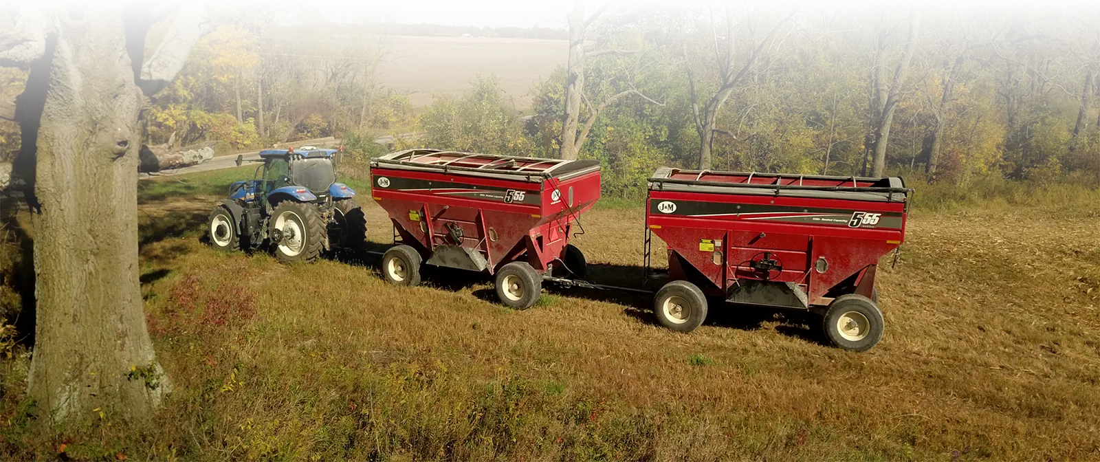 two 55 series gravity wagons being pulled in a field