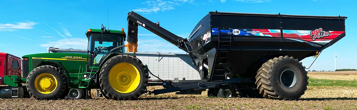 black grain cart with patriotic decal unloading into semi