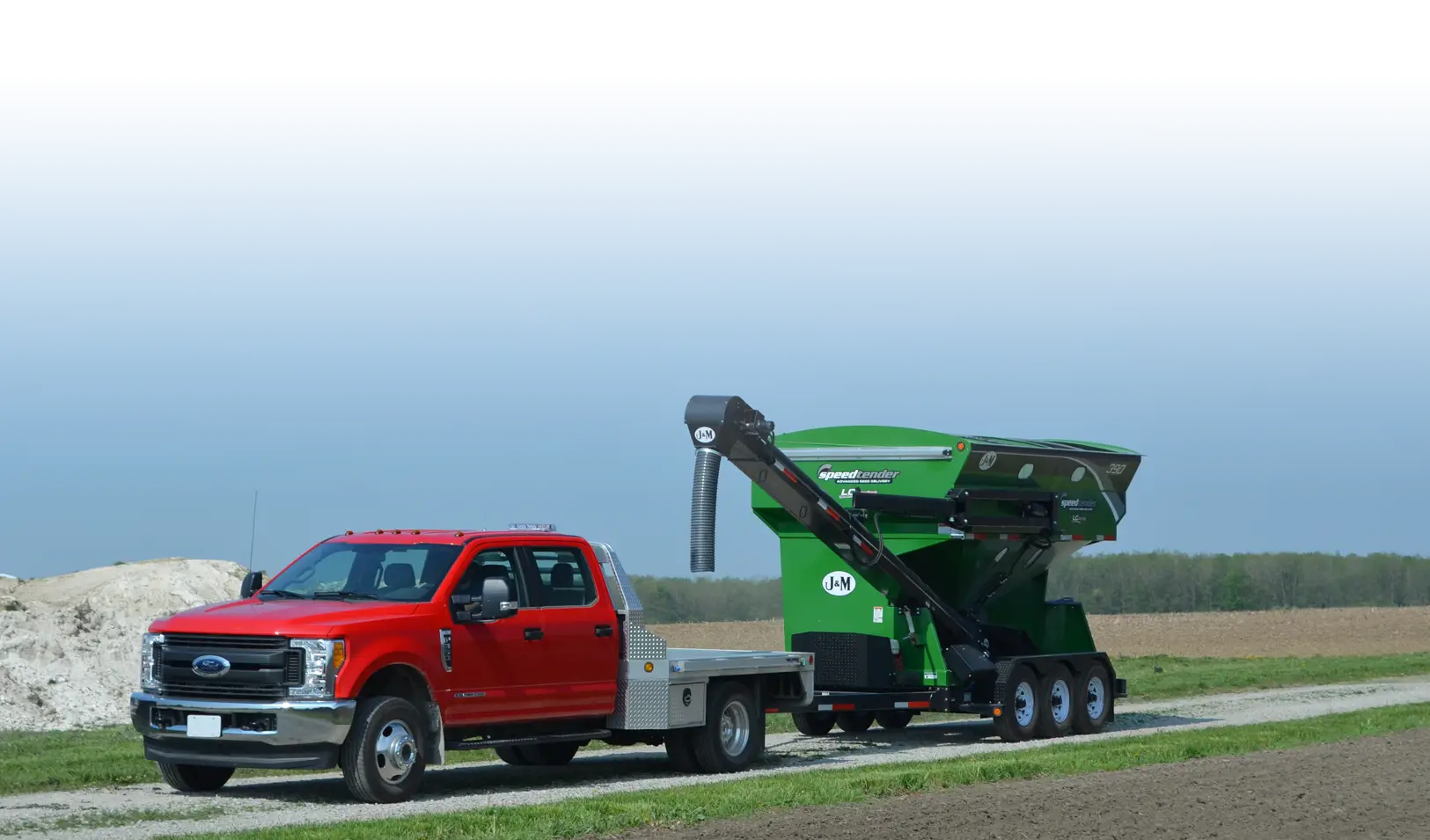 Green LC 390 Seed Tender being pulled down a road